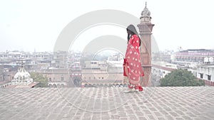 An indian young girl walking on the roof wearing a red kurta payjama