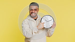 Indian young man showing time hour on wall office clock, ok, thumb up, approve, hurry up, deadline
