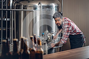 Indianr male manufacturer presenting craft beer in the microbrewery.