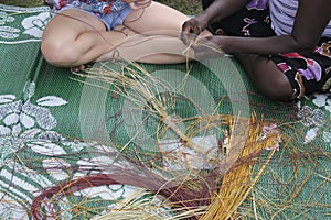 Indigenous Australians aboriginal woman teaching a tourist Aboriginal basket weaving