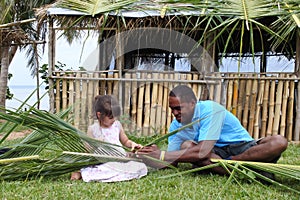 Indigenous Fijian man teach young tourist girl how to create a b