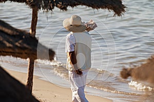 An indigenous man with a hat sells nuts on the beach
