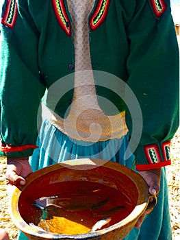 Indigenous woman showing the caught fish in Islas flotantes de los Uros on the lake Titicaca, Peru photo