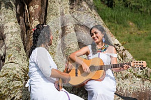 Indigenous women playing music in the nature with their instruments.