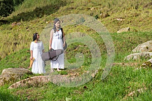 Indigenous women walking in the nature with their instruments.