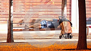 Indigent man sleeping on a bench in a park. Homeless and social problem concept. Empty copy space photo