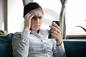 Indignant unhappy Indian woman looking at smartphone screen photo