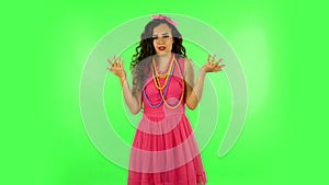 Indignant woman throwing up hands expressing she is innocent, twists his finger at his temple. Green screen at studio