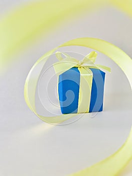 Indigo Gift box at the end of the spiral yellow ribbon, white background, vertical.