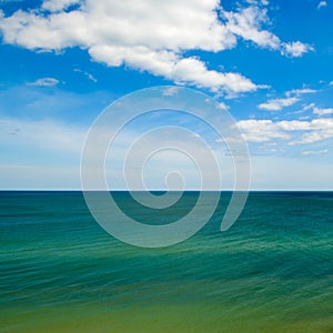 An indigo ocean and a bright blue sky with white clouds