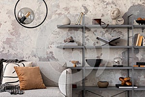 Indiustral style of modern living room with gray sofa with plaid, and rack with books and personal accessories. Gray concrete wall