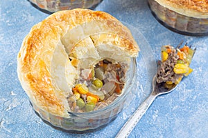 Individual beef pot pie or deep dish pie in ramekin, crust broken open to show inside, horizontal