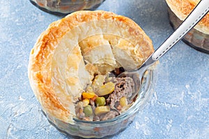 Individual beef pot pie or deep dish pie in ramekin, crust broken open to show inside, horizontal