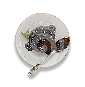 An individual chocolate sponge cake, with a sticky chocolate sauce, on a white plate with a spoon, isolated on white