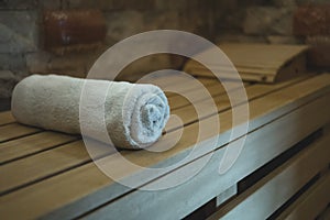 An individual cotton towel on a wooden bench prepared for a sauna client. Comfortable classical steam sauna amenities. Client-orie