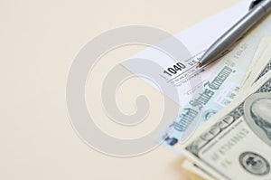 1040 Individual Income tax return form with Refund Check and hundred dollar bills on beige background