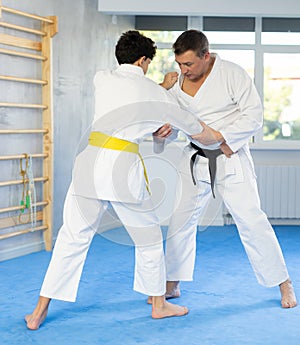 Individual judo lesson for teenager - guy and trainer are sparring in gym