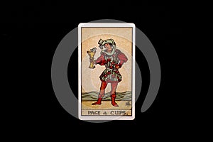 An individual minor arcana tarot card isolated on black background. Page of cups.