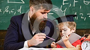 Individual schooling concept. Father with beard, teacher teaches son, little boy. Kid studies individually with teacher