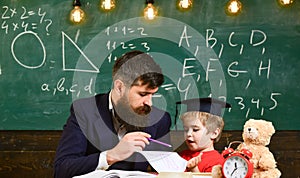 Individual schooling concept. Kid studies individually with teacher, at home. Father with beard, teacher teaches son