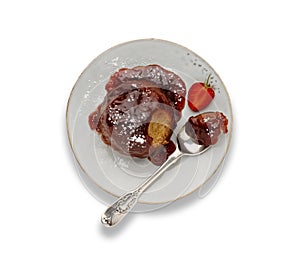 An individual strawberry sponge cake, with a sticky strawberry sauce, on a white plate with a spoon, isolated on white with a