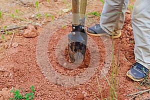An individual using hand post hole digger to dig a fence post
