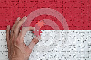 Indonesia flag is depicted on a puzzle, which the man`s hand completes to fold