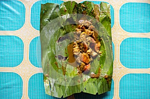 Indonesian dish PEPES IKAN on banana leaf on plate top view centered