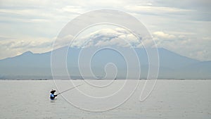 Indonesian fisherman catches a fish during a tropical rain.