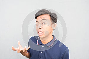 Indonesian guy with a blue t-shirt madly looking at the camera on a white background