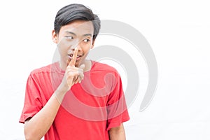 Indonesian guy with a red t-shirt looking down and silencing someone on a white background