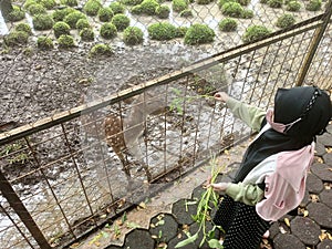 Indonesian little girl with mask feeding a small deer