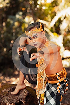 Indonesian man dancing with the golden crown while wearing shirtless golden clothes on his body