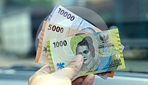 Indonesian man hand holding rupiah money. Indonesian currency. cash in hand concept and close up view