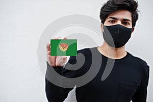 Indonesian man wear all black with face mask hold East Nusa Tenggara flag in hand isolated on white background. Provinces of photo