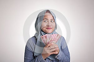 Indonesian Muslim Woman Holding Rupiah Money and Thinking