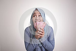 Indonesian Muslim Woman Holding Rupiah Money and Thinking