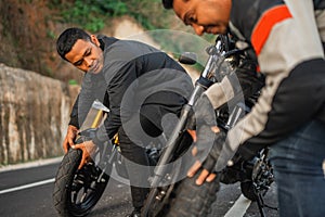 indonesian rider checking inspecting motorbike wheel