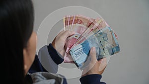 Indonesian rupiah banknote held by a woman, 50,000 and 100,000 rupiah