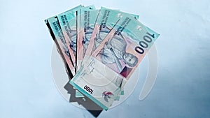 Indonesian rupiah banknotes with a nominal value of one thousand rupiah on a white background