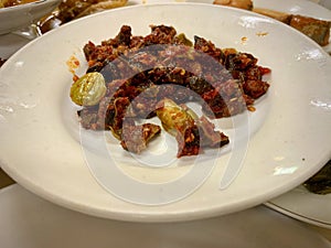 Indonesian spicy chicken liver and gizzard dish on a white plate