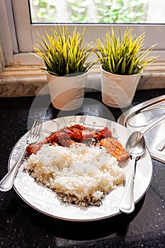 Indonesian style dish including white rice, fried chicken with serundeng shredded fried coconut, and sambal paste put on a plate