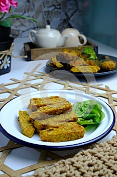 Indonesian traditional meal named tempe goreng, fried fermented soybean cake on white plate