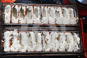 Indonesian traditional meal "kue rangi" making process of rice dough placed on semi circle shaped frying pan photo