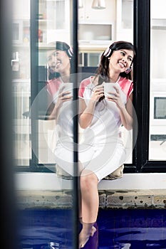 Indonesian woman enjoying music at home with coffee