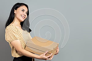 Indonesian woman posing holding a pizza box while looking up