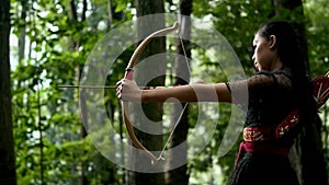 Indonesian Women with black dresses shoot the target with a flying arrow from