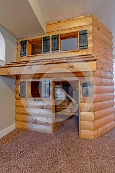 Indoor cabin playhouse for children made of brown logs built inside a house