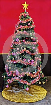 indoor Christmas tree with bulbs, strung garland, lights and topped with a yellow star