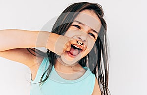 Indoor closeup portrait of the naughty little girl grimacing and smiling broadly with mustache drawing on her index finger put it